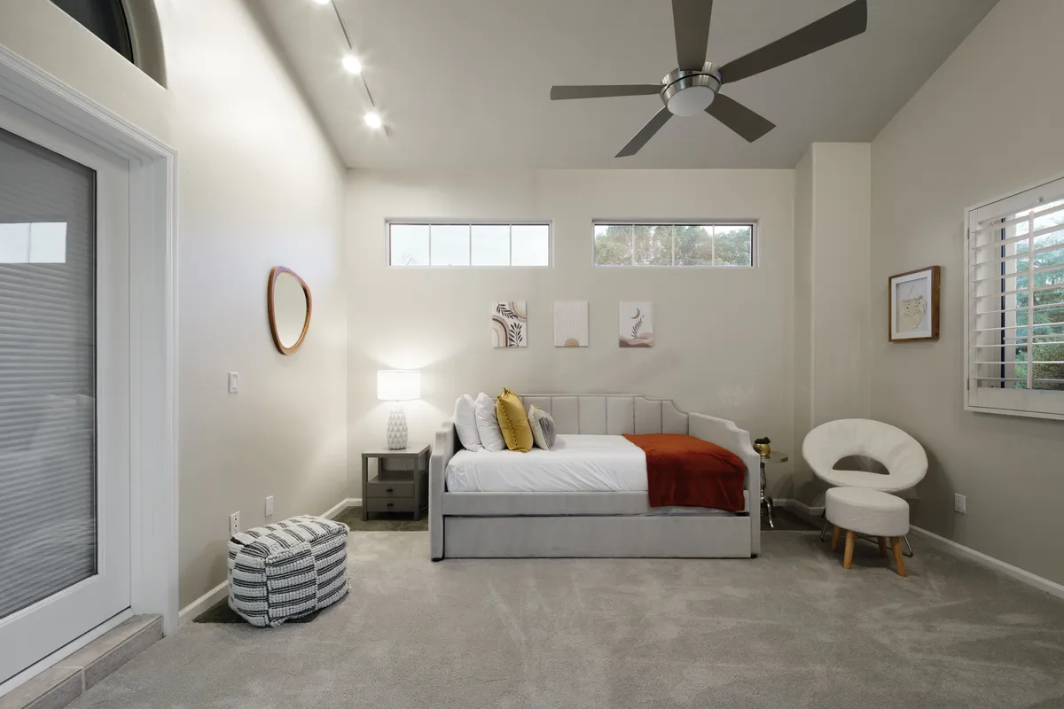 A tranquil and cozy corner bedroom scene with a bed layered in soft bedding and a red throw, a nightstand with lamp, a decorative chair, and gentle window light setting a peaceful mood perfect for relaxing or quiet reading.