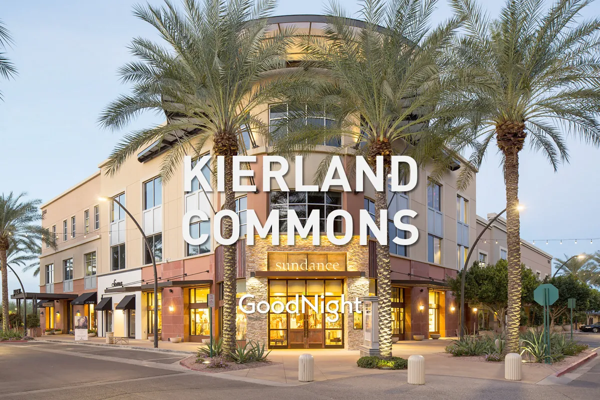 The image showcases lively storefronts framed by towering palm trees, with illuminated signage and people visible along the walkways. The festive energy suggests an active shopping and dining area, likely representing one of Scottsdale’s premier retail destinations such as Scottsdale Quarter or Kierland Commons.