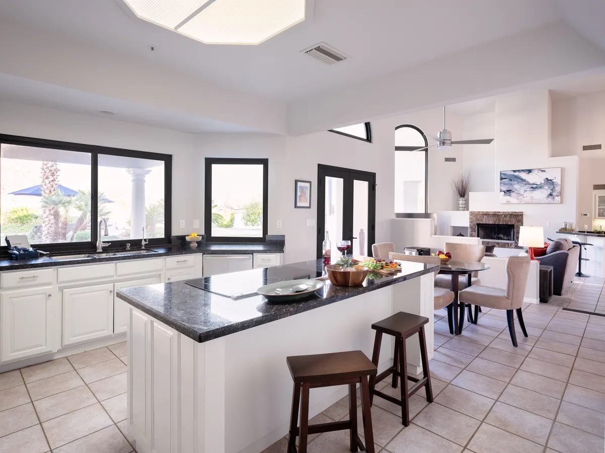 A vibrant open-plan kitchen and dining area with a kitchen island featuring bar seating, modern appliances, large windows, a fireplace, and an adjacent dining space. The scene is lively yet inviting, ideal for group meals, celebrations, and casual breakfasts.